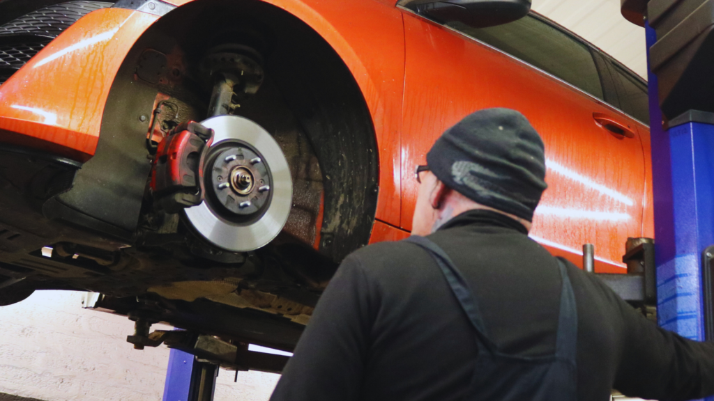 Image of technician looking up at car being worked on